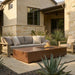 Outdoor patio with a rectangular concrete fire pit table and comfortable seating area in front of a house.