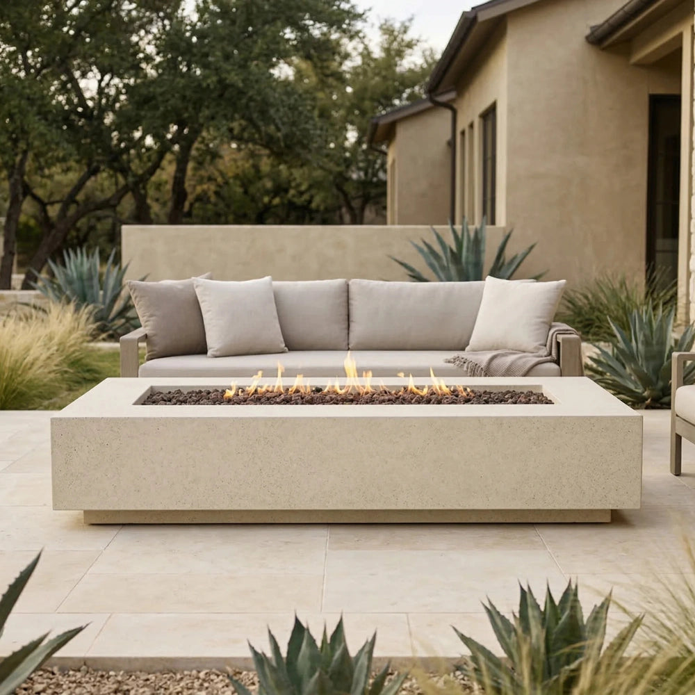Outdoor patio with a rectangular concrete fire pit table and sofa set in a garden setting.