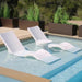 Two white in-pool chaise loungers and a round side table partially submerged on a pool ledge.
