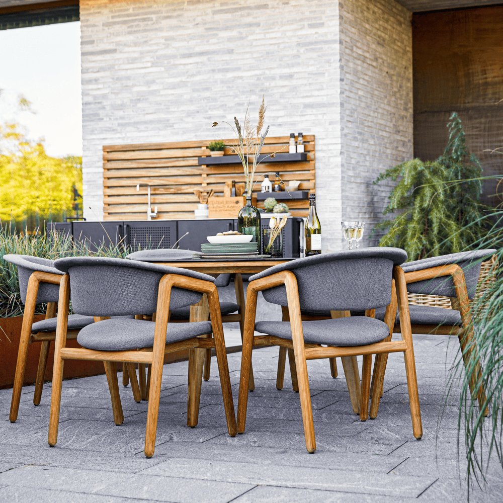 Boxhill's Luna Outdoor Dining Armchair Lifestyle image with teak round table at patio