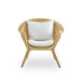 Natural rattan outdoor lounge chair with white cushions featuring curved arms and a woven backrest.