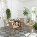 Natural rattan outdoor dining armchair beside a matching round wooden dining table in a bright indoor setting.