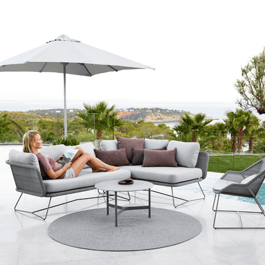 Boxhill's Major Parasol w/ Sliding System | 3x3 m lifestyle image with a woman sitting down on module sofa beside the pool