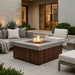 Outdoor patio with square outdoor concrete fire pit table with an element of teak slats, seating area, and plants.