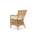 Natural rattan outdoor dining armchair viewed from the angled rear featuring an open woven back.