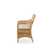 Natural rattan outdoor dining armchair viewed from the side featuring an open woven frame.
