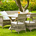 Gray rattan outdoor dining side chair with white cushions beside a matching 2-seater sofa and dining table.