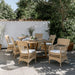 Natural rattan outdoor dining armchair with white cushions beside a matching wooden dining table on a patio.