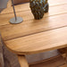 Close-up of a teak oval outdoor dining table with a structured vase on top