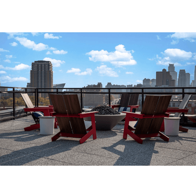 A rooftop patio with several red outdoor club chairs with dark brown wood grain seat and backrest position around round concrete fire bowl