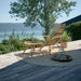 Natural rattan outdoor footstool beside a matching lounge chair on a round woven rug.