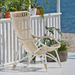 White rattan outdoor high-back lounge chair on a seaside patio with potted plants.