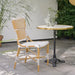 Natural rattan outdoor dining side chair with black and white woven wicker beside a round marble-top bistro table.