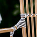 Close-up of a natural rattan outdoor bistro armchair featuring black and white woven wicker detailing.