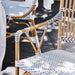Close-up of the natural rattan outdoor bistro armchair armrest and black and white woven wicker seat.