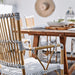 Close-up of the natural rattan outdoor bistro armchair featuring the backrest, armrest and black and white woven seat.
