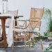 Natural rattan outdoor bistro armchair featuring black and white woven wicker beside a wooden dining table.