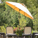 A large patio umbrella in a warm yellow-gold shade stands open between two outdoor mesh chairs in a garden setting with green foliage in the background.