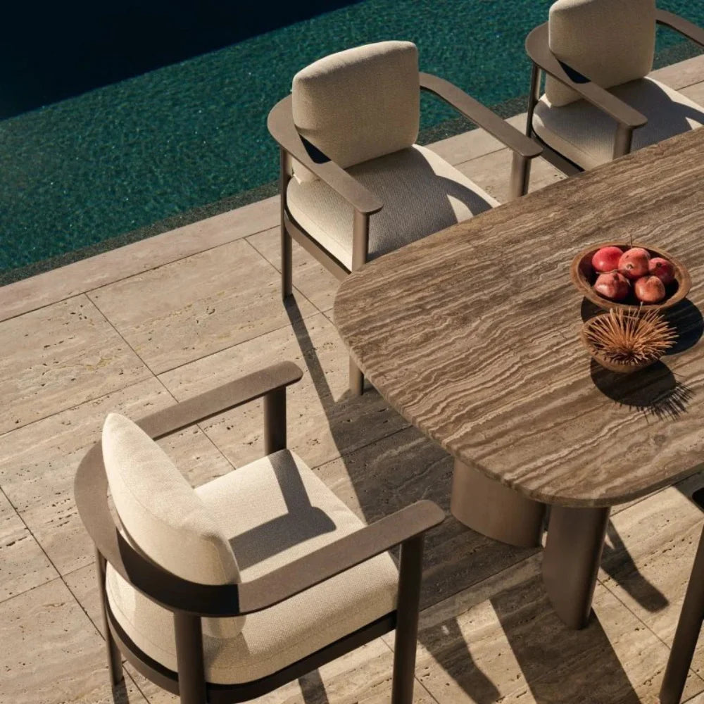 A cozy outdoor aluminum curved-edge dining table and aluminum dining chairs arranged near a clear blue pool, perfect for enjoying meals outdoors.