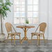 Round teak outdoor café table beside matching natural rattan dining side chairs in a bright indoor setting.