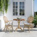 Square teak outdoor café table with a natural teak pedestal base beside matching natural rattan dining armchairs.