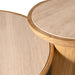 Close-up of two round nesting tables with light beige travertine stone tops and natural wood bases, showing the textured stone surface and warm wood grain.