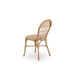 Natural rattan outdoor dining side chair featuring an open woven back viewed from the angled rear.