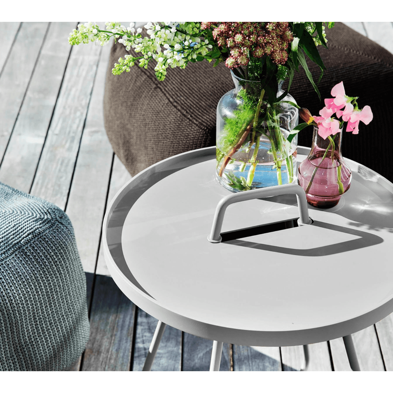 Boxhill's On-The-Move white outdoor round side table with flower in a vase on it between light grey and brown outdoor fabric footstool 