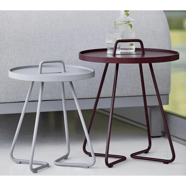 Boxhill's On-The-Move Side Table small size in Light Grey color and large size in Maroon color with glass of water and a bottle container on it