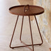 Brown aluminum outdoor side table with a handle on a stone floor.
