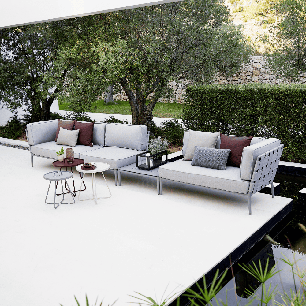 Boxhill's On-The-Move white, light grey and maroon outdoor round side table with light grey outdoor sectional sofa placed in patio