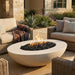 Outdoor patio with outdoor concrete oval fire pit, couches, and plants in a residential setting