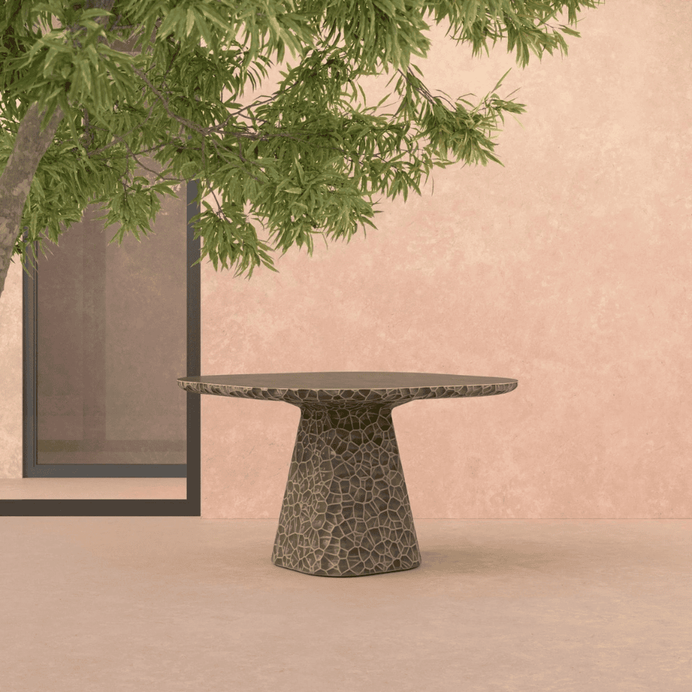A concrete square shaped dining table that has an abstract honeycomb texture reminiscing hammered metal.