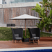 Boxhill's Peacock dark grey outdoor wing highback chair with 2 small dark grey round table and a white parasol placed on poolside