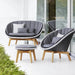 Modern outdoor patio furniture set including a curved gray lounge chair with a matching footstool both with light wood legs and gray cushions, positioned on a white patio.