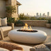 Outdoor patio with white oval conrete fire pit, chairs, and city skyline view