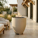 Outdoor patio with a tall cylinder-shaped concrete white fire pit and seating area