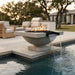 Outdoor square concrete fire pit with water feature and pedestal bottom next to a pool