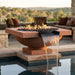 Outdoor concrete square fire pit bowl with water feature next to a pool, surrounded by patio furniture.