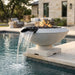 Concrete outdoor round fire pit with water feature by a pool