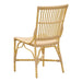 Natural rattan outdoor dining side chair featuring an open woven back viewed from the angled rear.