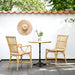 Natural rattan outdoor dining side chair beside a round café table on a sunny patio.