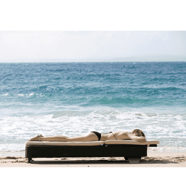Boxhill's Presley dark grey Outdoor daybed with white cushion with a woman sunbathing on it placed on beach shore
