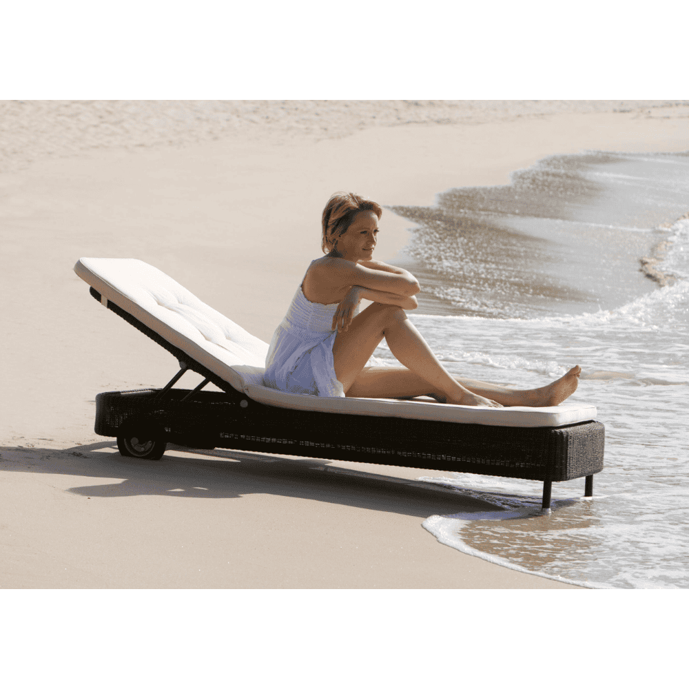 Boxhill's Presley dark grey outdoor daybed with white cushion with a woman sitting on it placed on beach shore
