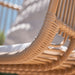 Close-up of the natural rattan outdoor hanging swing chair with woven rattan frame detailing.