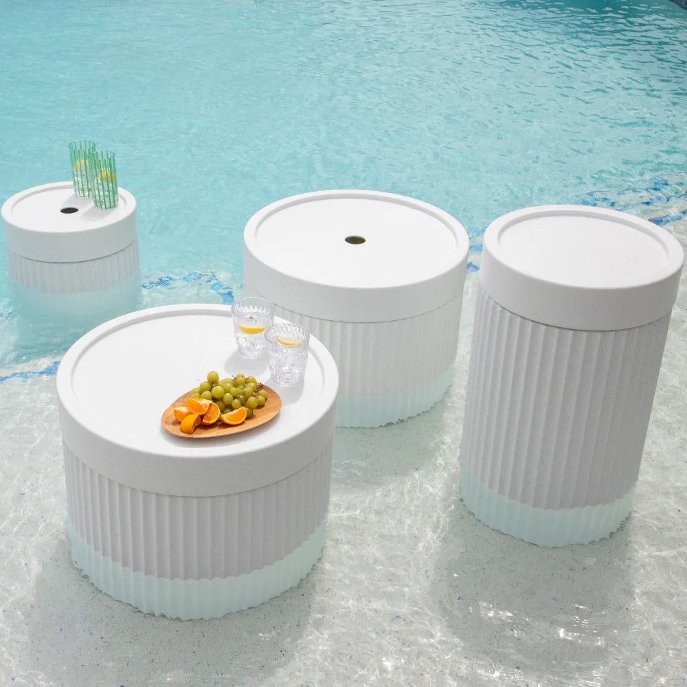 Four round white tables featuring an assortment of fruits and beverages on their surfaces.