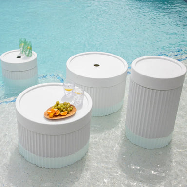 Four round white tables featuring an assortment of fruits and beverages on their surfaces.
