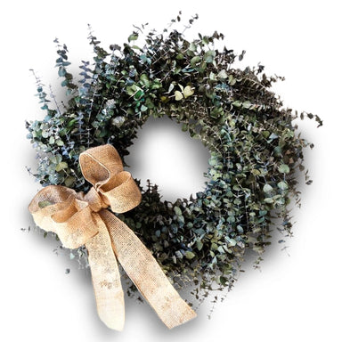 Decorative rustic eucalyptus wreath with a natural burlap bow on a white background.
