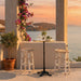 White rattan outdoor bar stools beside a round teak bar table with a black pedestal base.