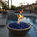A two brown round concrete fire and water bowls filled with blue fire glass with flames on top placed on a tiled wall beside the pool